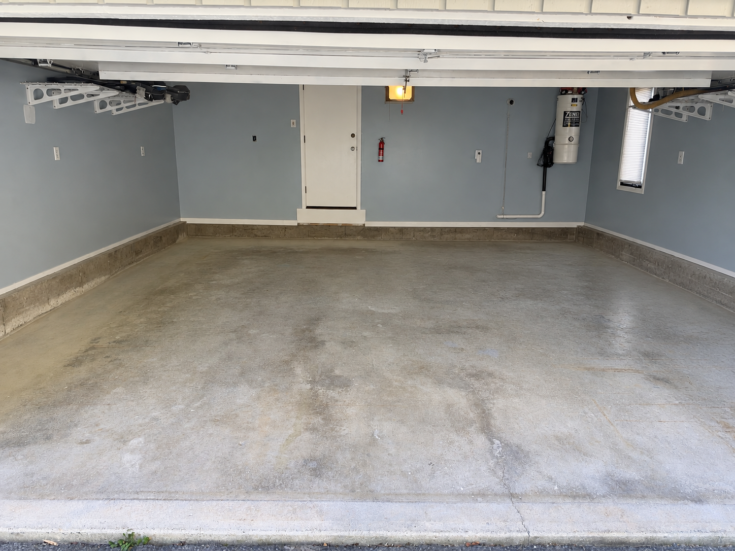 Worn concrete garage floor and uncoated stem walls before coating in West Springfield, MA